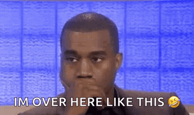 A Man In A Suit Is Sitting In Front Of A Blue Wall And Covering His Mouth With His Hands . GIF