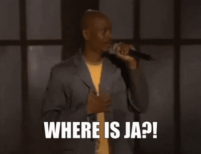 A Man In A Suit Is Sitting In Front Of A Microphone And Says `` Help Me Ja Rule '' . GIF
