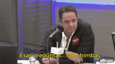 A Man In A Suit Is Sitting In Front Of A Microphone With The Words Esas Preguntas Tan Chimbas Written Below Him GIF