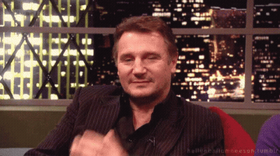 A Man In A Suit Is Sitting In Front Of A Window With A Cityscape In The Background GIF