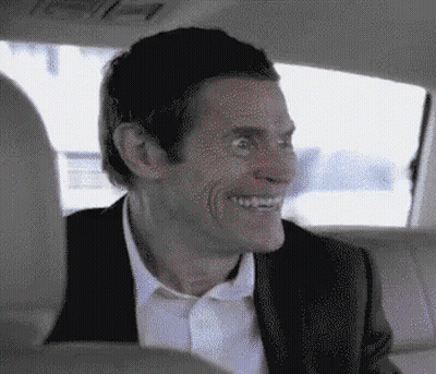 A Man In A Suit Is Sitting In The Back Seat Of A Car And Smiling . GIF