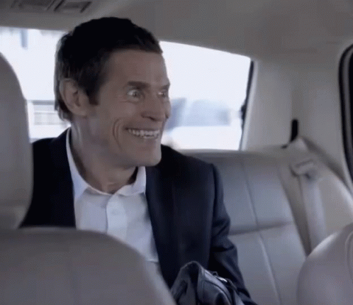 A Man In A Suit Is Sitting In The Back Seat Of A Car Smiling GIF