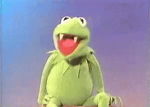 A Man In A Suit Is Sitting Next To A Muppet Frog . GIF