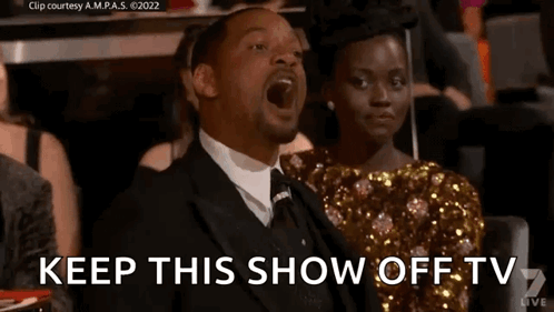 A Man In A Suit Is Sitting Next To A Woman In A Gold Dress . GIF