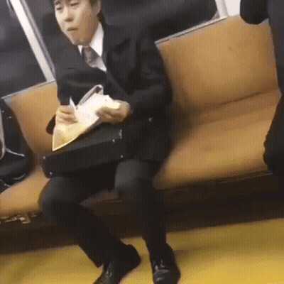 A Man In A Suit Is Sitting On A Couch Holding A Briefcase And A Book . GIF