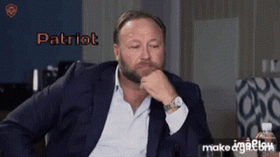 A Man In A Suit Is Sitting With His Hand On His Chin And The Word Patriot Is On The Screen GIF
