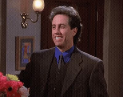 A Man In A Suit Is Smiling And Holding Up A Sign That Says " I Like " GIF