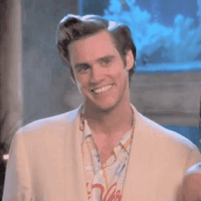 A Man In A Suit Is Smiling And Looking At The Camera . GIF