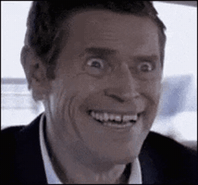 A Man In A Suit Is Smiling And Making A Funny Face In A Car . GIF