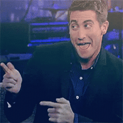 A Man In A Suit Is Smiling And Pointing GIF