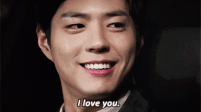 A Man In A Suit Is Smiling And Saying I Love You . GIF