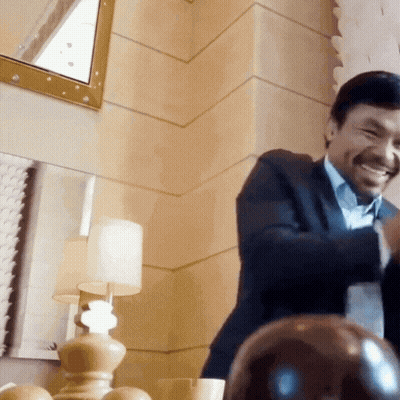 A Man In A Suit Is Smiling In Front Of A Mirror And Lamp GIF
