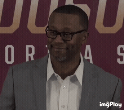 A Man In A Suit Is Smiling In Front Of A Sign That Says Ucsd GIF