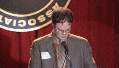 A Man In A Suit Is Speaking Into A Microphone In Front Of A Sign That Says " Social " GIF