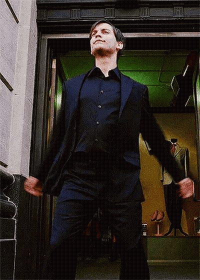 A Man In A Suit Is Standing In A Doorway With His Arms Outstretched GIF