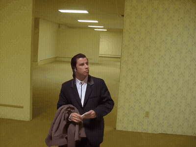 A Man In A Suit Is Standing In A Hallway GIF