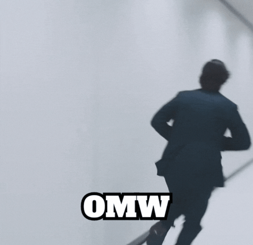 A Man In A Suit Is Standing In A Hallway And The Word Omw Is On The Bottom GIF