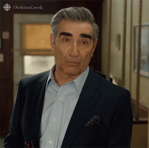 A Man In A Suit Is Standing In A Hallway With #Schitts Creek Written On The Bottom GIF