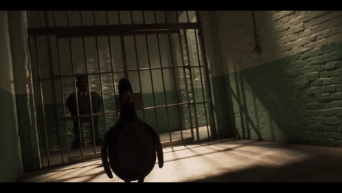 A Man In A Suit Is Standing In A Jail Cell GIF