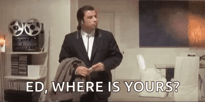 A Man In A Suit Is Standing In A Living Room Holding A Jacket And Talking To Someone . GIF