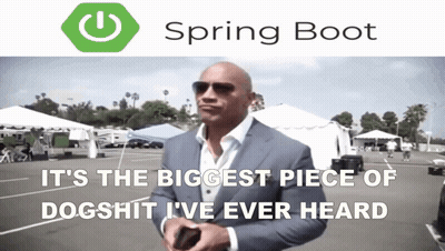 A Man In A Suit Is Standing In A Parking Lot With A Spring Boot Logo Behind Him GIF