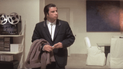 A Man In A Suit Is Standing In A Room GIF