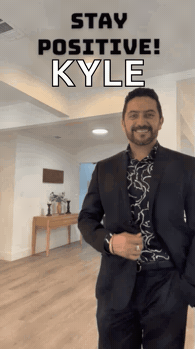A Man In A Suit Is Standing In A Room With The Words Stay Positive Kyle Behind Him GIF