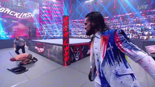 A Man In A Suit Is Standing In A Wrestling Ring With A Referee . GIF