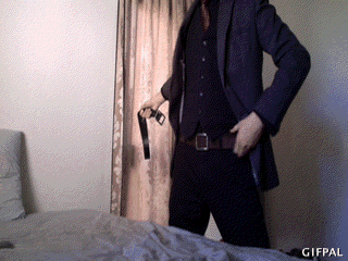 A Man In A Suit Is Standing In Front Of A Bed With A Gifpal Watermark On The Bottom GIF