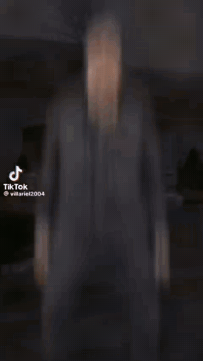 A Man In A Suit Is Standing In Front Of A Building In A Video . GIF