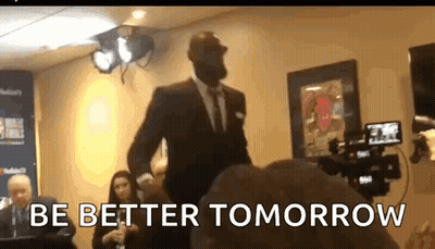 A Man In A Suit Is Standing In Front Of A Camera With The Words Be Better Tomorrow Written On The Bottom GIF