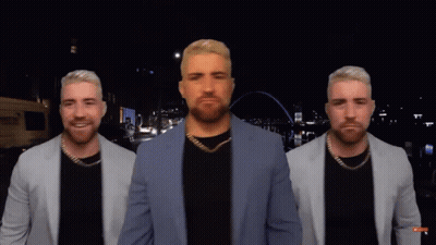 A Man In A Suit Is Standing In Front Of A City Skyline GIF