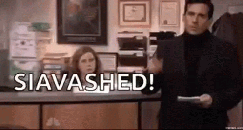 A Man In A Suit Is Standing In Front Of A Counter Holding A Piece Of Paper And Saying `` Siavashed ! '' GIF