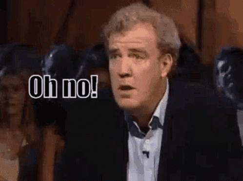 A Man In A Suit Is Standing In Front Of A Crowd And Says Oh No . GIF