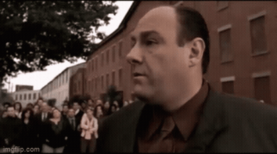 A Man In A Suit Is Standing In Front Of A Crowd Of People . GIF