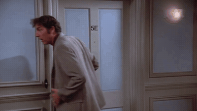A Man In A Suit Is Standing In Front Of A Door That Says 5E GIF