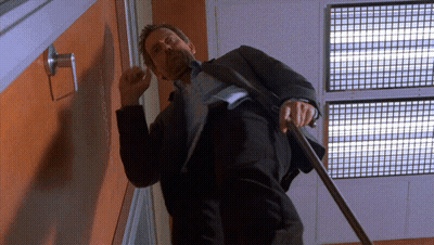 A Man In A Suit Is Standing In Front Of A Door With A Sign That Says ' Emergency Exit ' On It GIF