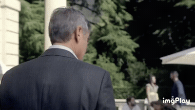 A Man In A Suit Is Standing In Front Of A Group Of People And A Sign That Says Imgplay On The Bottom GIF