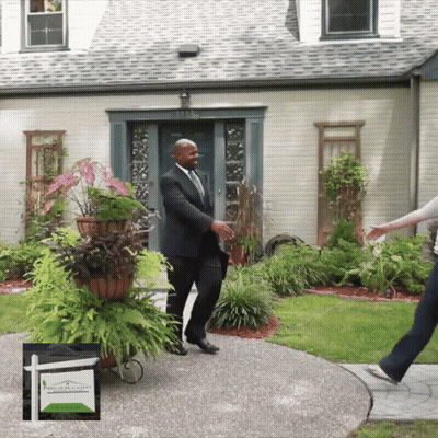 A Man In A Suit Is Standing In Front Of A House GIF
