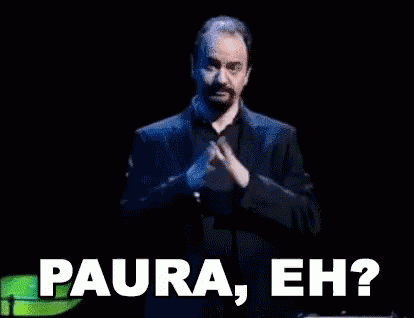 A Man In A Suit Is Standing In Front Of A Microphone And Says " Paura Eh " . GIF