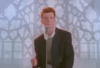 A Man In A Suit Is Standing In Front Of A Microphone . GIF