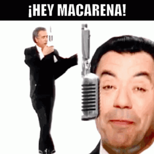 Man In Suit Stands In Front Of Microphone Saying Hey Macarena GIF