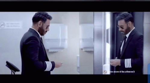A Man In A Suit Is Standing In Front Of A Mirror GIF