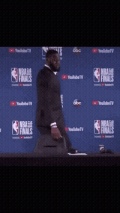 A Man In A Suit Is Standing In Front Of A Nba Finals Sign GIF