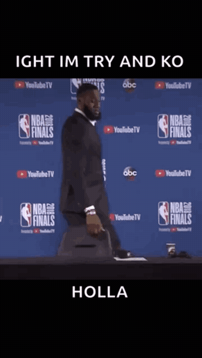A Man In A Suit Is Standing In Front Of A Nba Finals Wall GIF