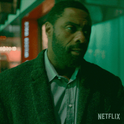 A Man In A Suit Is Standing In Front Of A Netflix Logo GIF