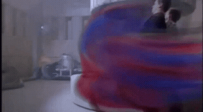 A Man In A Suit Is Standing In Front Of A Red And Blue Object In A Room . GIF