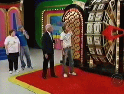 A Man In A Suit Is Standing In Front Of A Roulette Wheel With The Number 65 On It . GIF