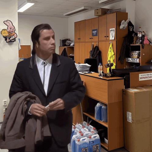 A Man In A Suit Is Standing In Front Of A Shelf With A Sign On It That Says Platt GIF