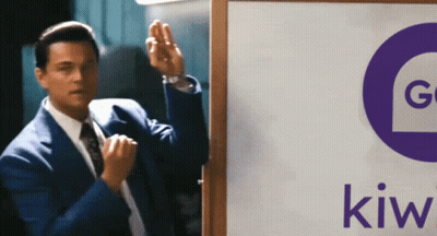 A Man In A Suit Is Standing In Front Of A Sign That Says Kiwi GIF